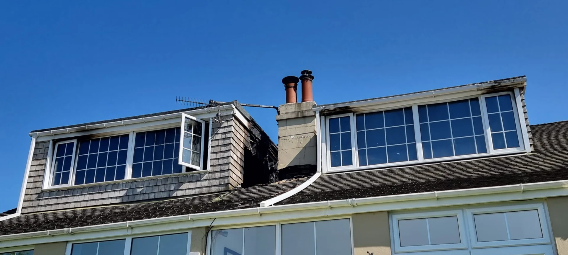 House roof with open window and chimneys.