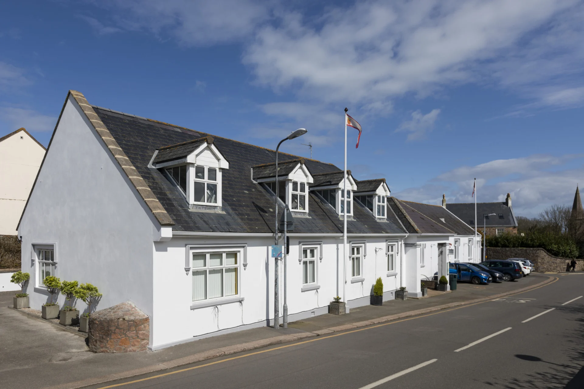 White building with dormer windows and flag.