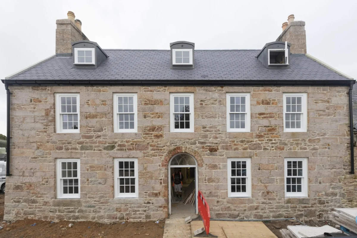 Stone house with dormer windows and chimney.