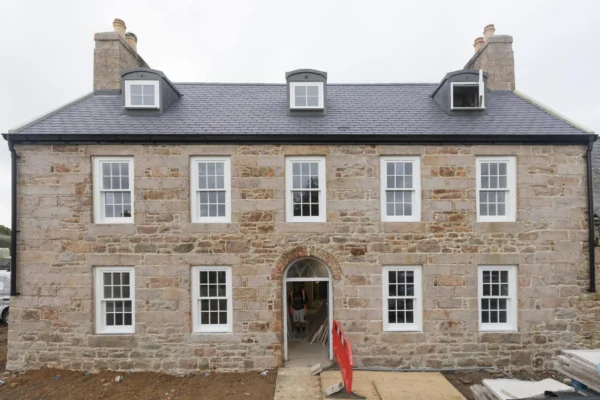 Stone house with dormer windows and chimney.