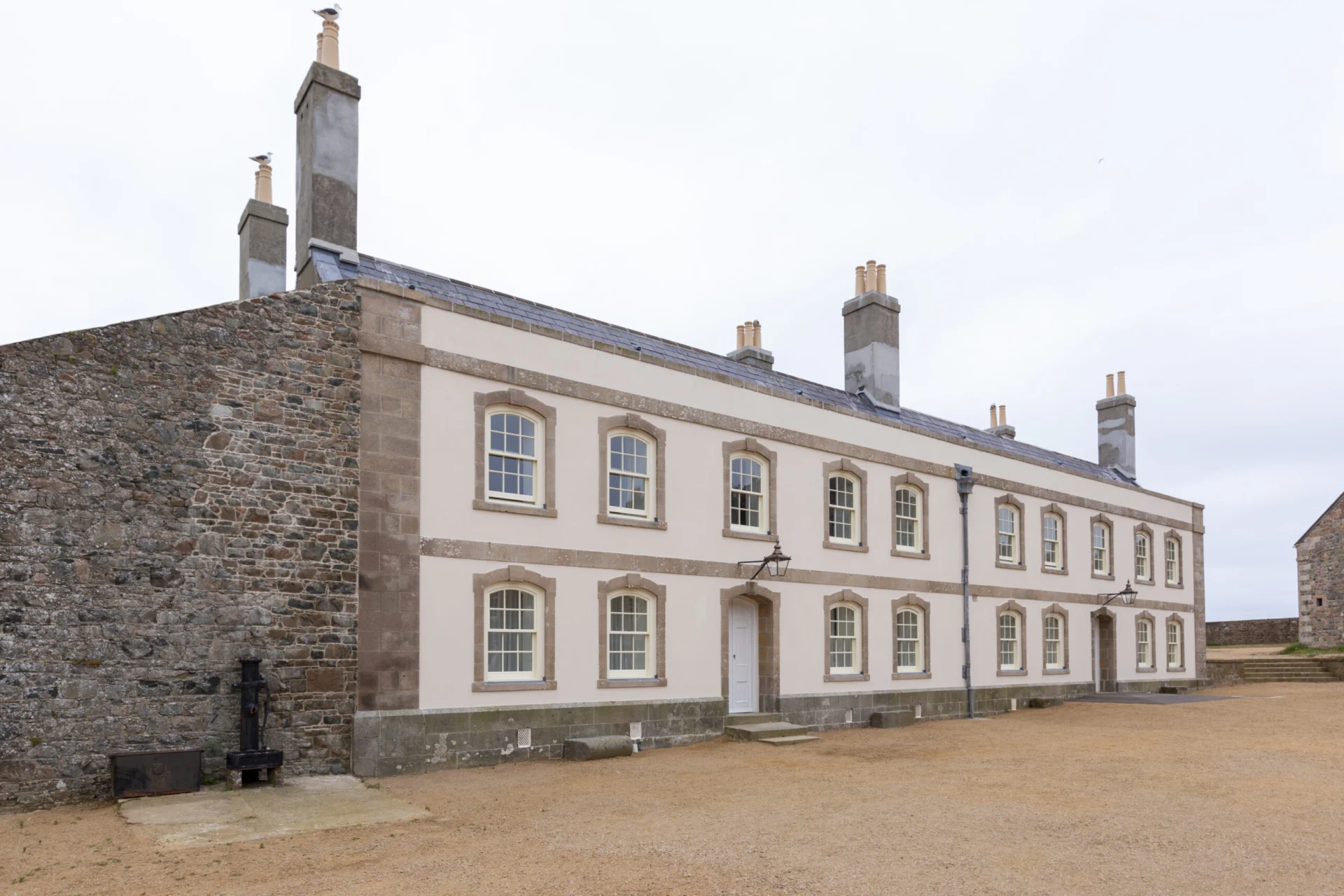 Historic stone building with multiple chimneys and windows.
