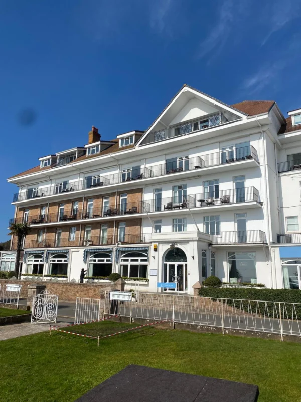 Large seaside hotel building with balconies and windows.