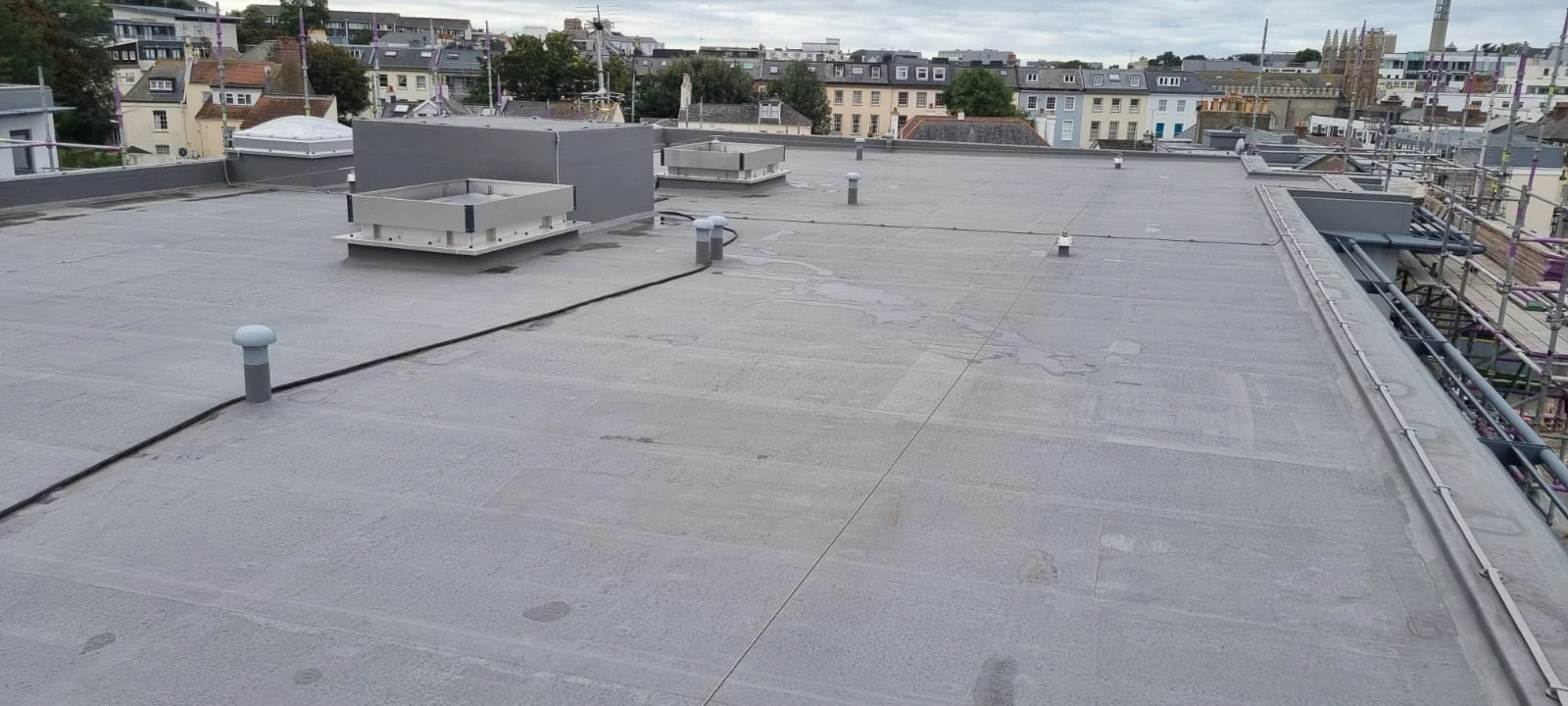 Flat rooftop with cityscape and ventilation systems.